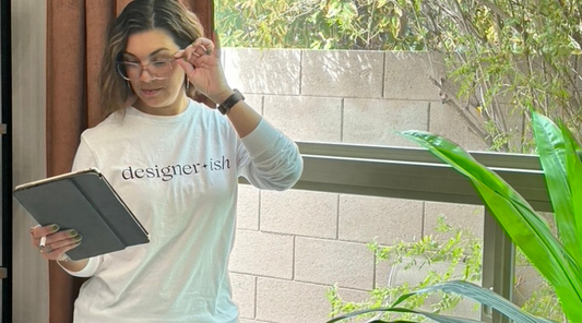 Woman holding an ipad wearing a white long sleeve t-shirt that says Designerish in black letters