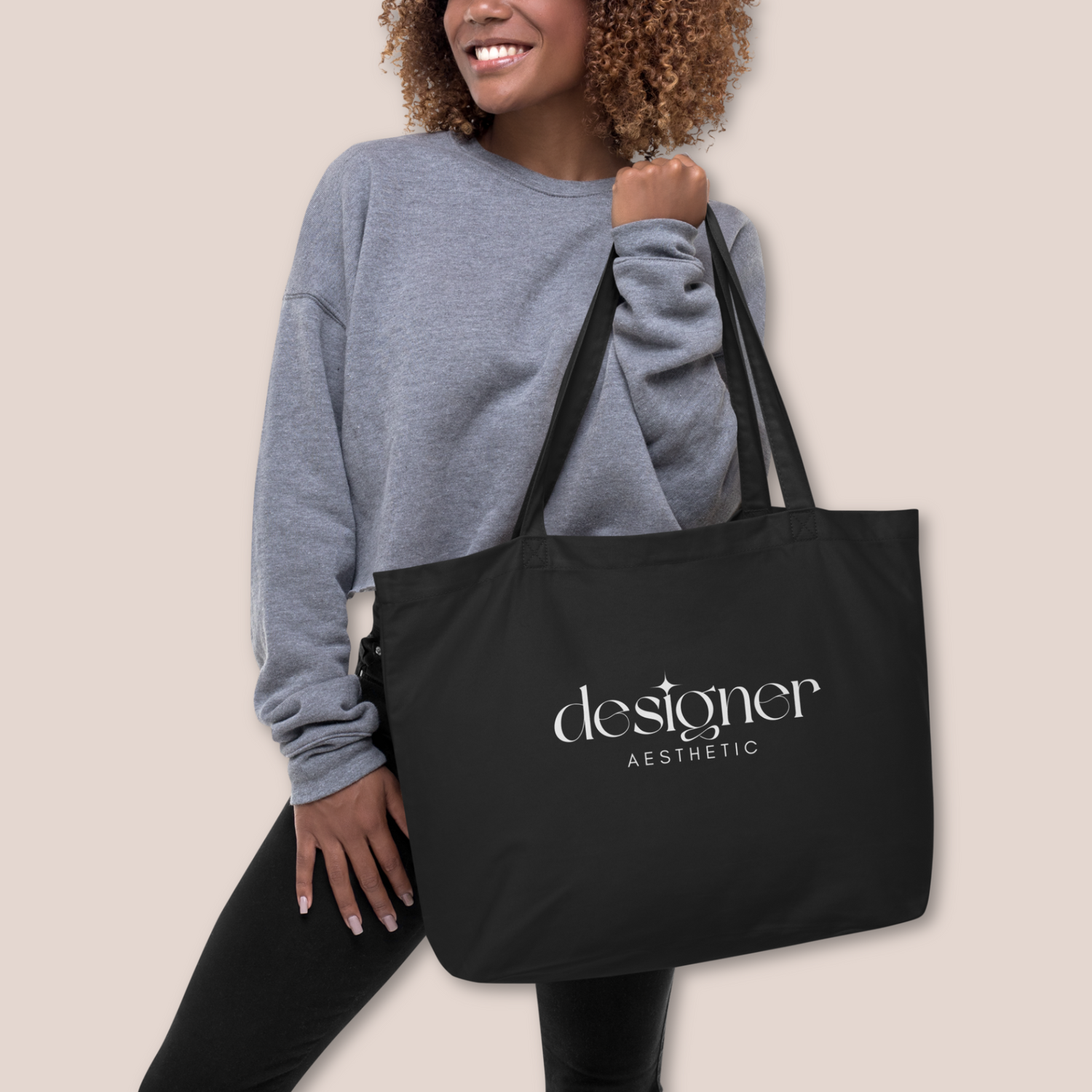 Woman holding black canvas tote bag showcasing Designer Aesthetic text in white ink